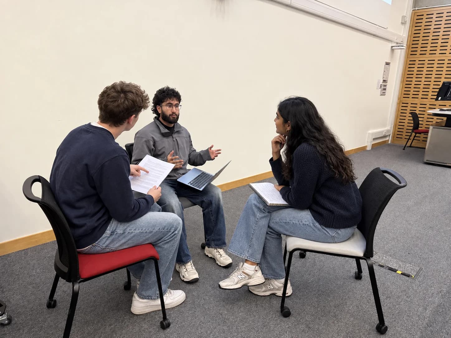 A tutor giving practical guidance to two students working through application questions